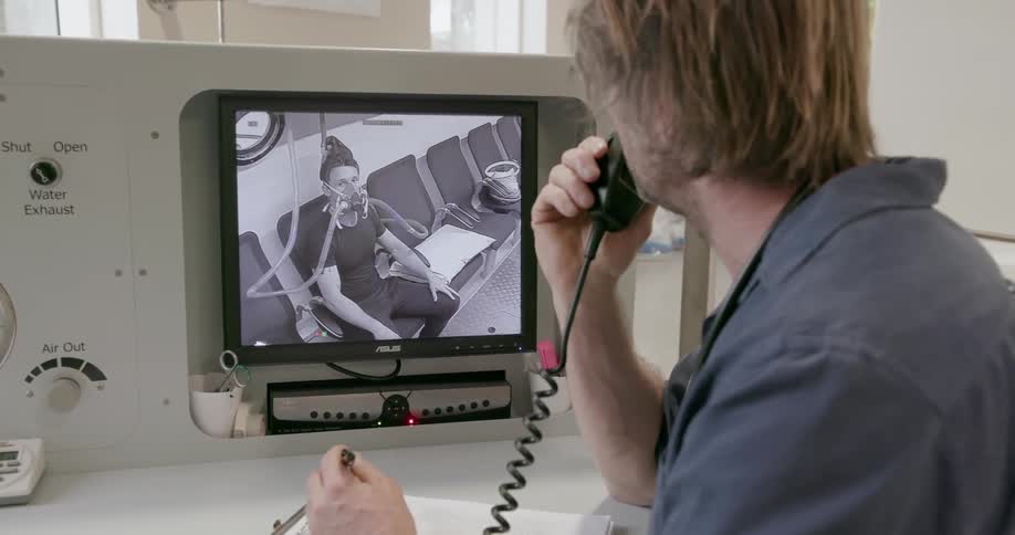 Man speaks through a walkie talkie while looking at a monitor