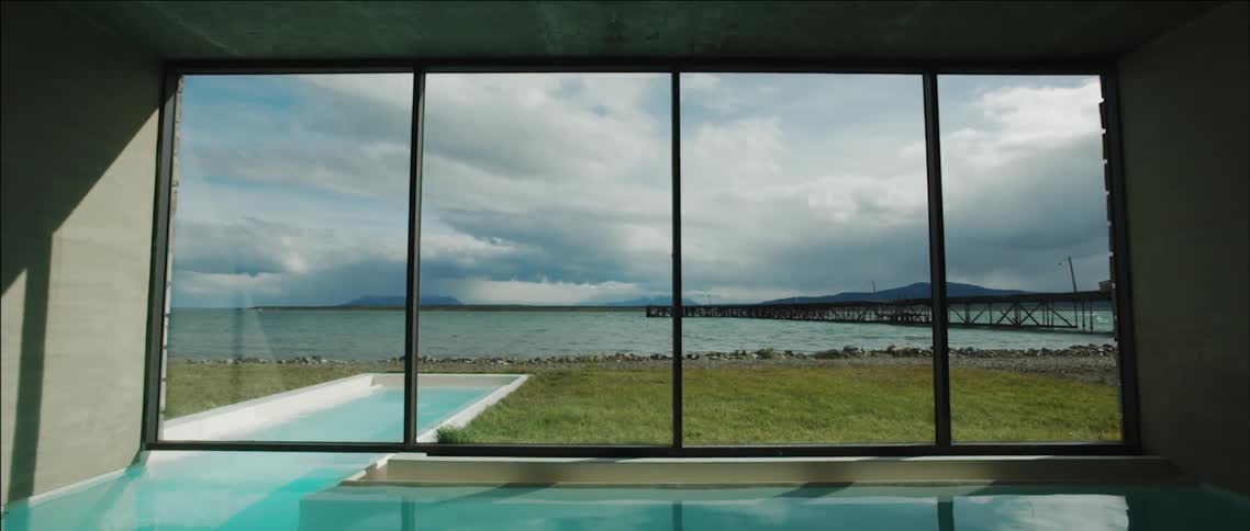 The view from an enclosed pool area of a building out to a large body of water