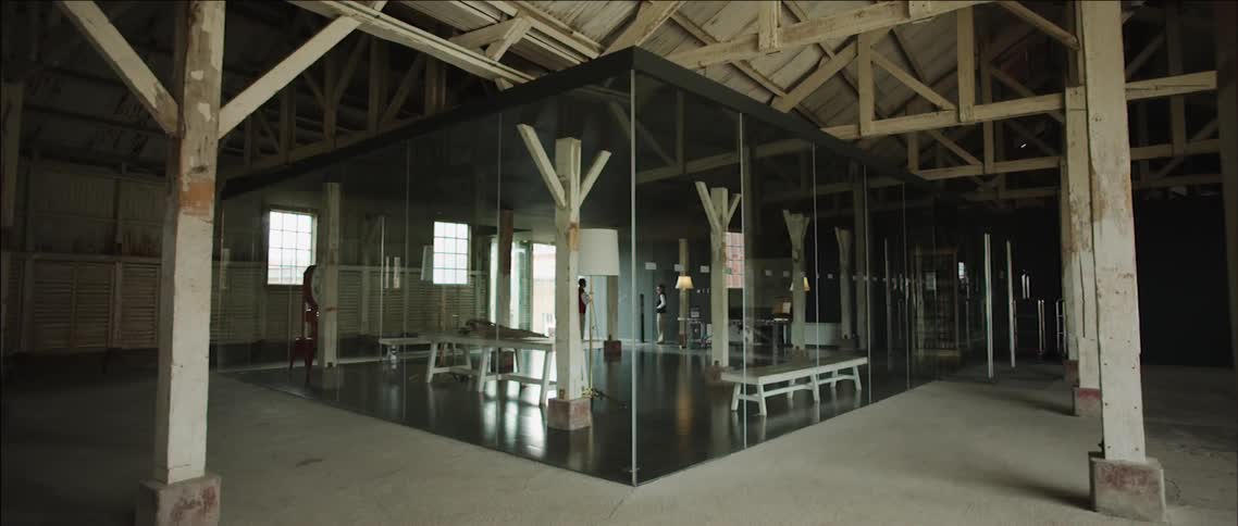 Two people stop and talk in a glass enclosed area of an old building