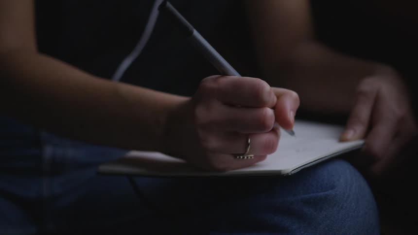 A person writes on paper held on their leg