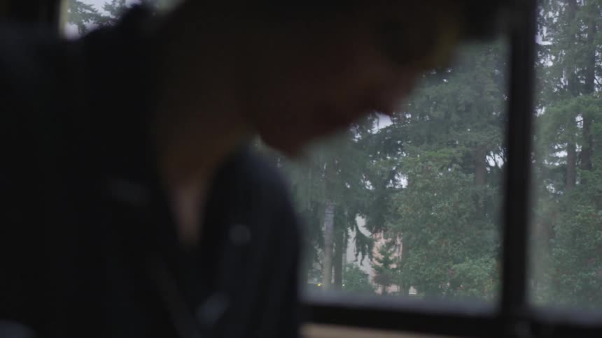 Silhouette person stands in front of a window looking down