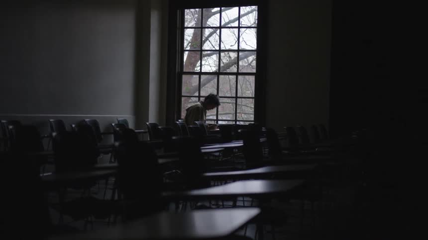 Boy sits in dark classroom next to window