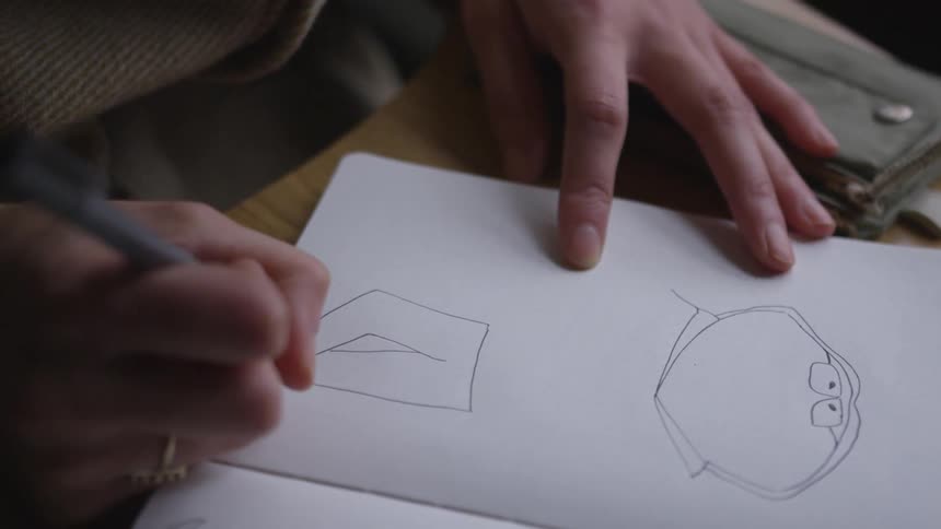 Person draws a cartoon character in a notebook