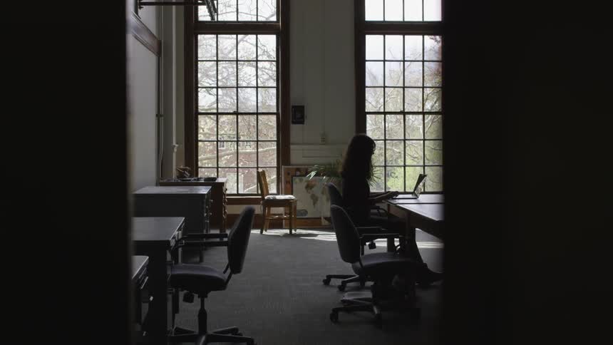 Woman sitting on a table while typing on a laptop