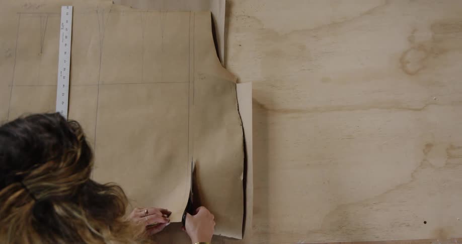A woman is cutting some paper on a large table