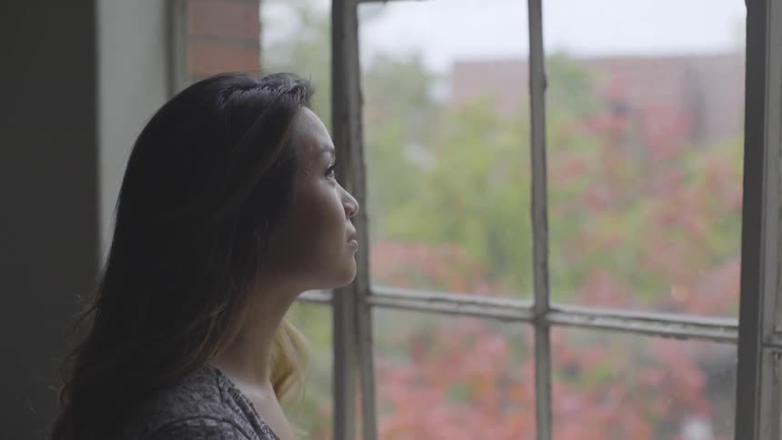 A young woman looks out of a georgian window