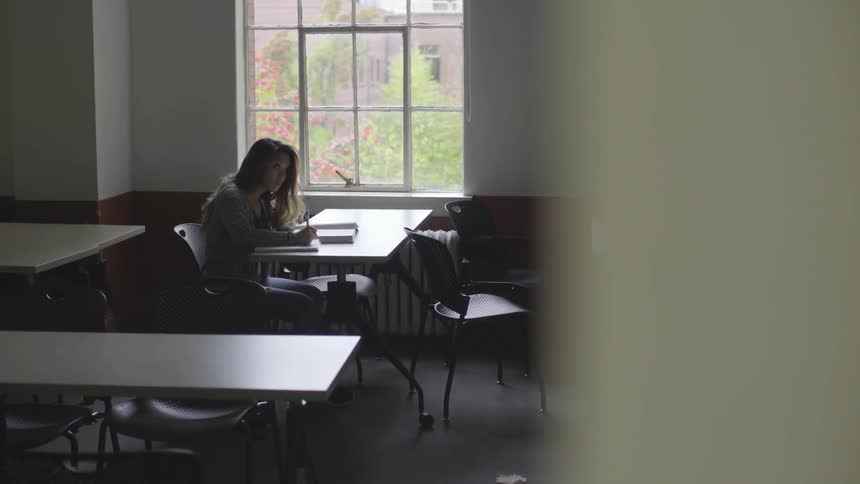 A student is writing in a notebook indoors