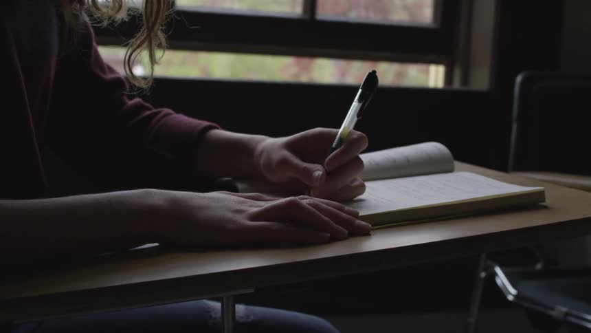 Woman sitting on a desk writing on a notepad