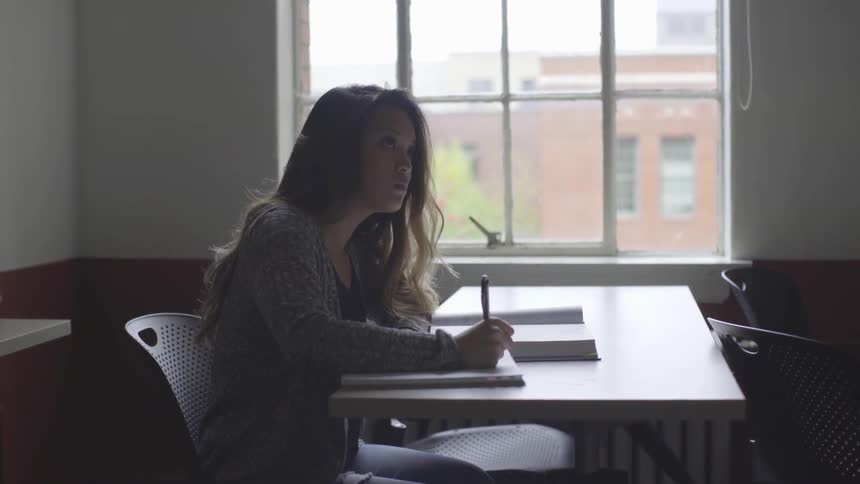 Student sits at a table writing in a notebook