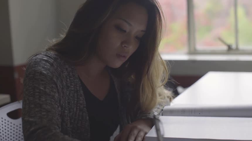 Woman sits at desk and writes in notebook