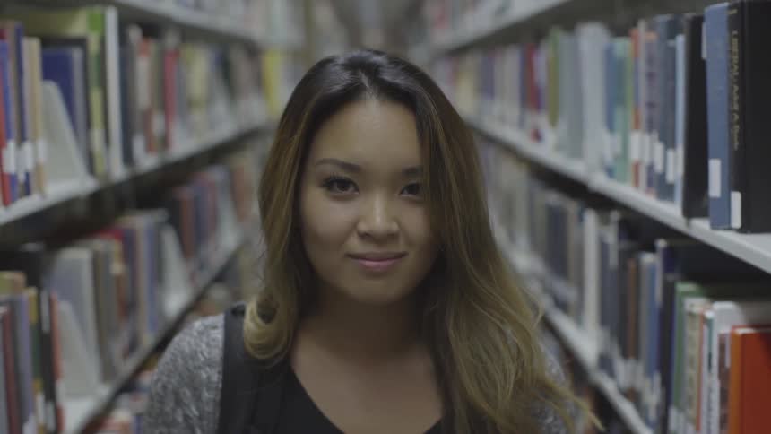 A woman stands in the library aisle