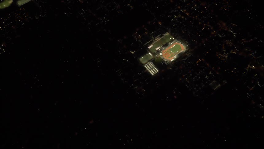 Lit sports stadium among dark cityscape