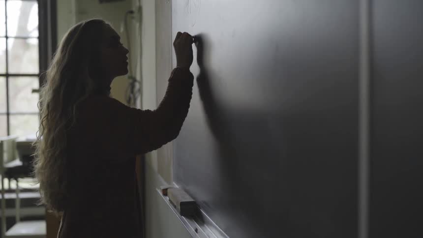 Woman writes on chalkboard