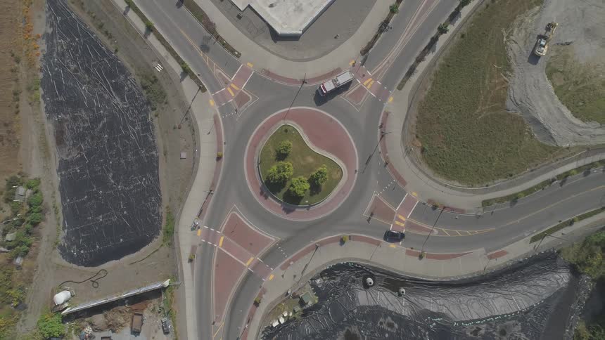 Cars driving through a four way intersection with a large circle roundabout in the middle