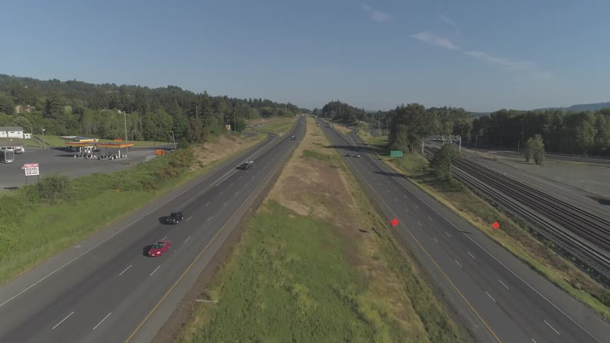Cars driving down a multi lane highway next to a railway