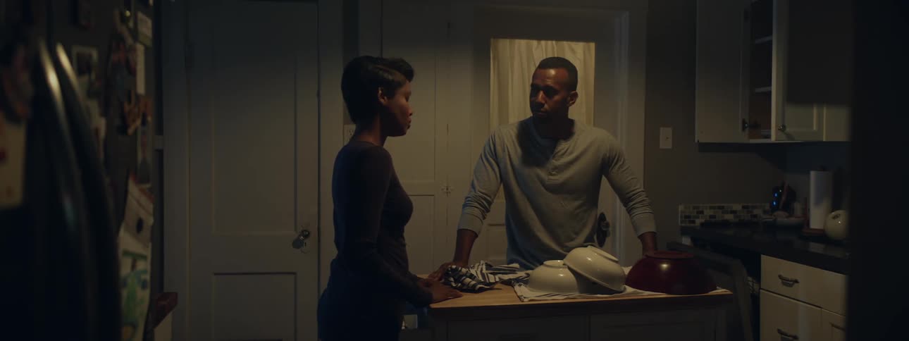 Man and woman hold hands in a dimly lit kitchen