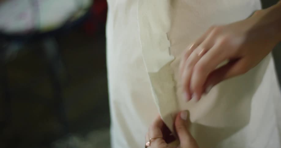 A woman works at pinning the seam of a garment