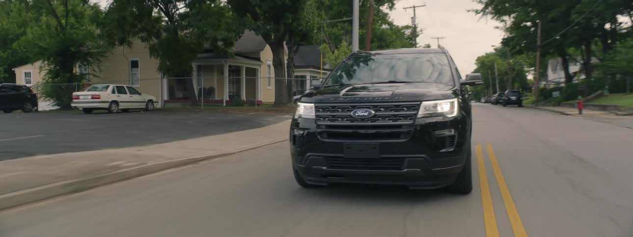 Black car drives down a residential street