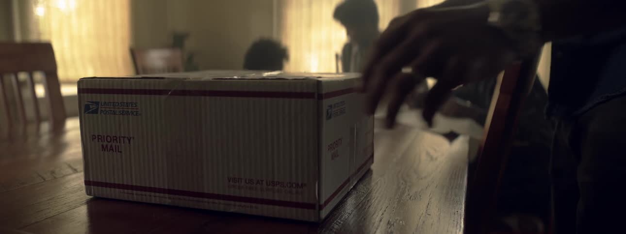 A person moves a priority mail package that sits on the table