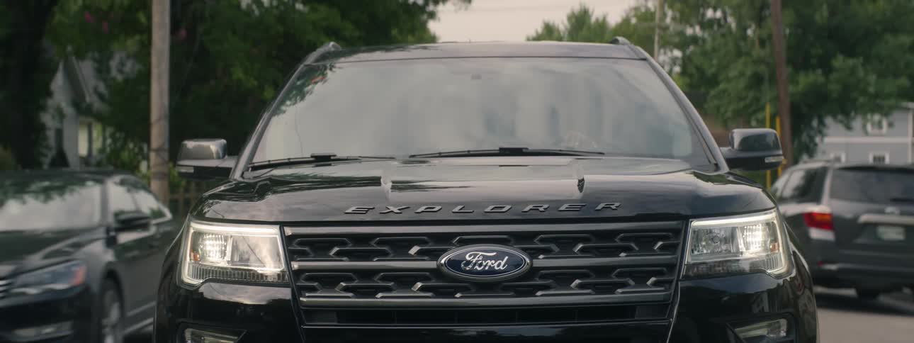Ford explorer drives along road among houses