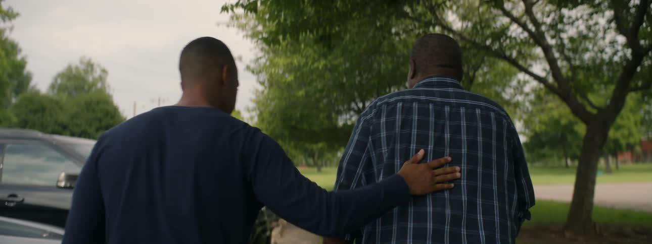 A man walks along a sidewalk with his father
