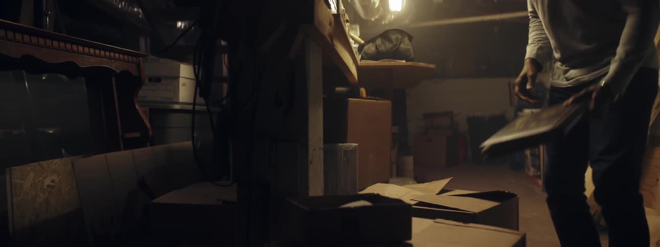 Person walks down stairs and turns on a basement light so they can get into a box