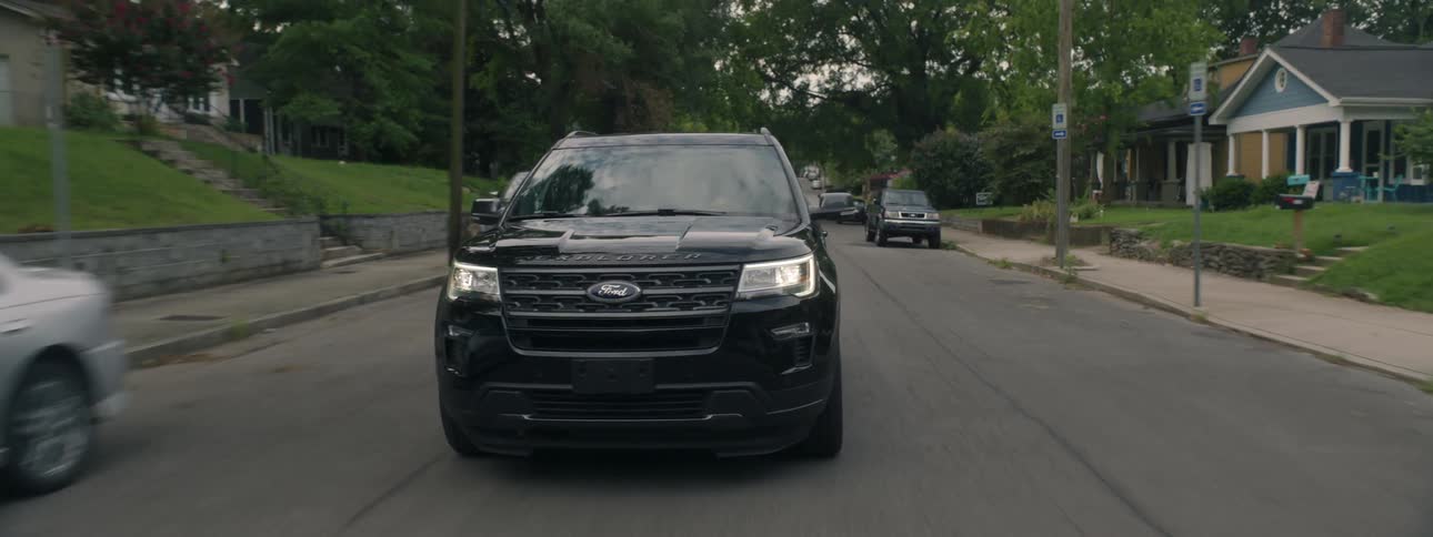 Car drives down street passing cars parallel parked