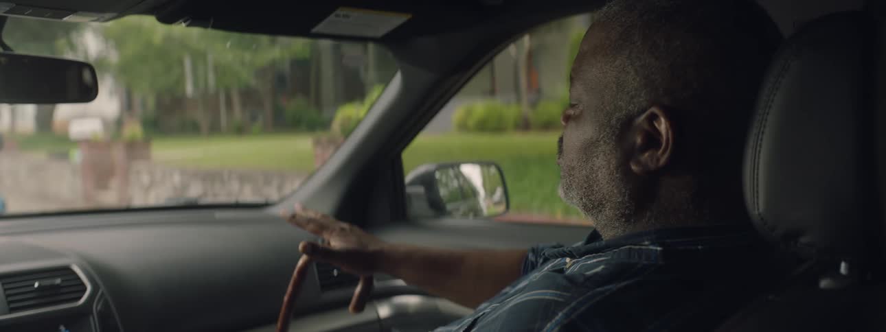 Elderly man sits in the front seat of a car looking out