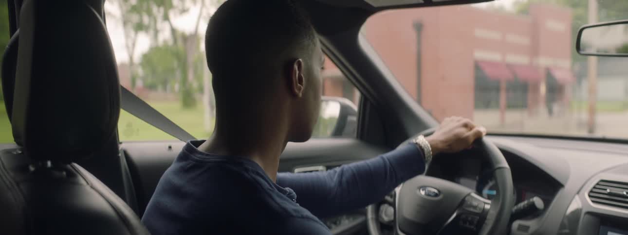 A man is driving a car in a neighborhood