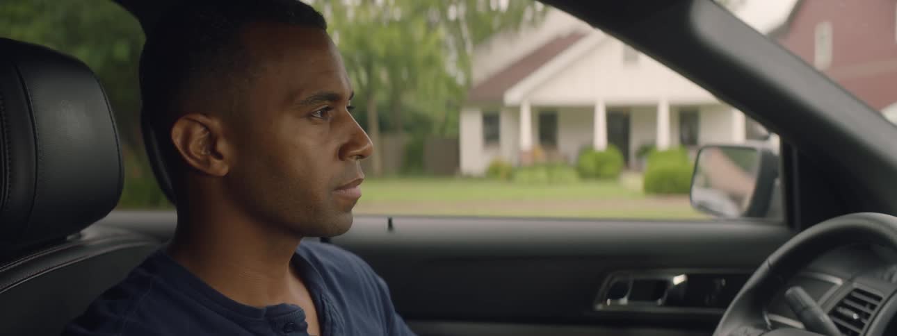 Man sits in a parked car and looks out