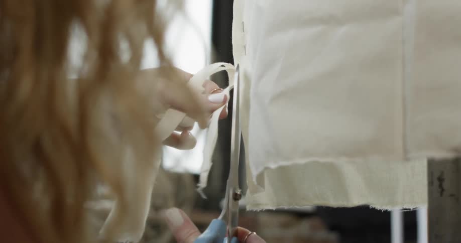 A woman cuts some fabric with scissors