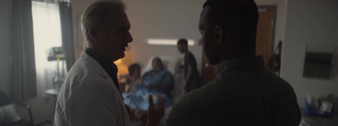 Doctor talks to a man while his family looks at things in the background