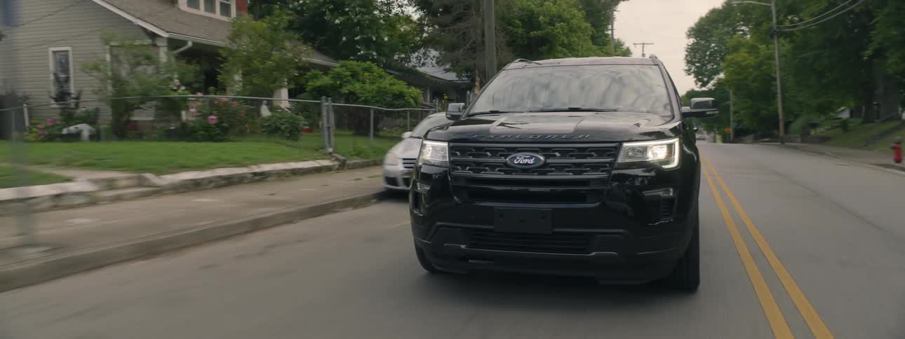 Black car drives down a residential street