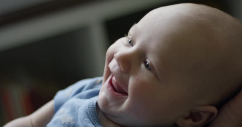 A baby smiles and waves its arm