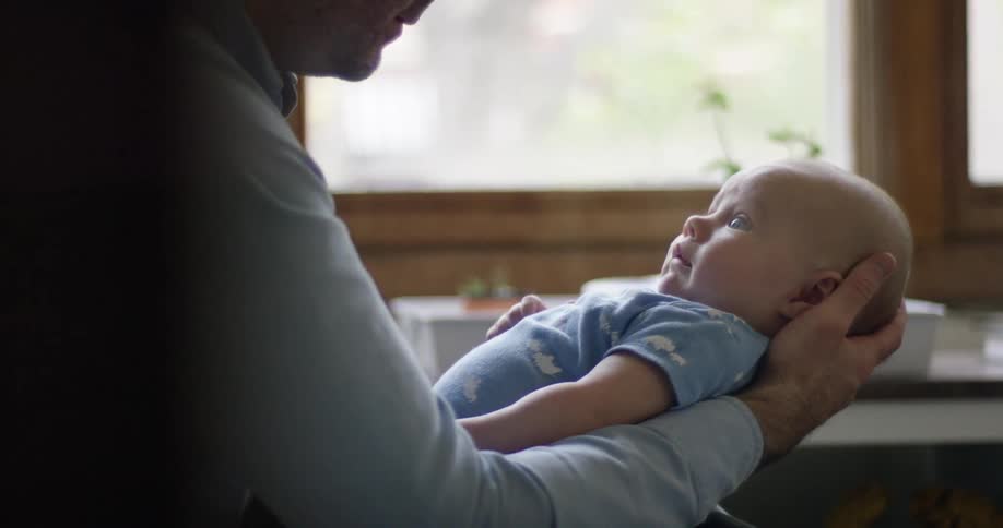 A man cradles a baby in his arm