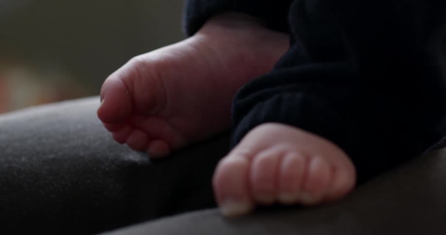A babies feet are curling and moving on a person's lap