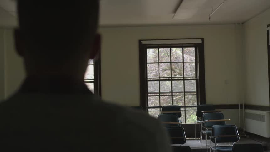 A blonde man stands at the head of a classroom