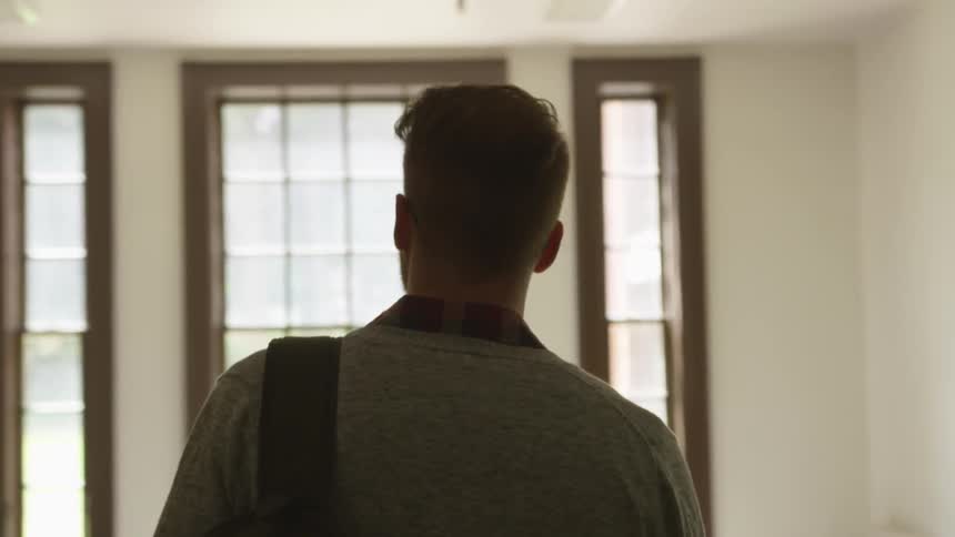 A man walks towards a brightly lit window