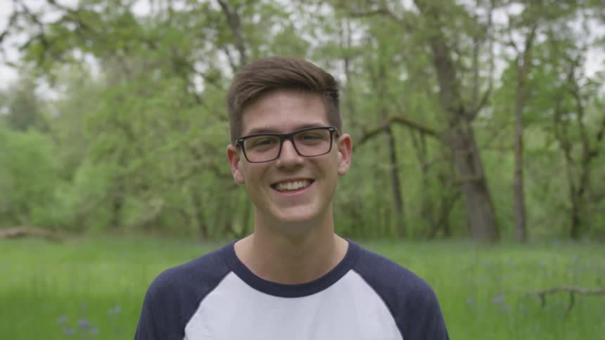 Man wearing glasses poses and smile in the forest by day