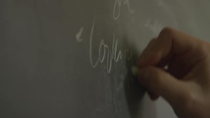 A person is writing on a chalkboard
