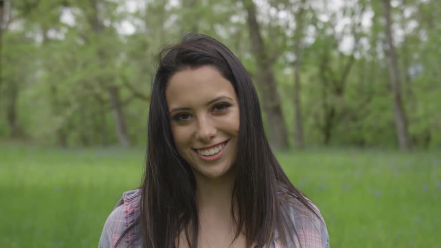 Young woman looks into camera while standing in grass