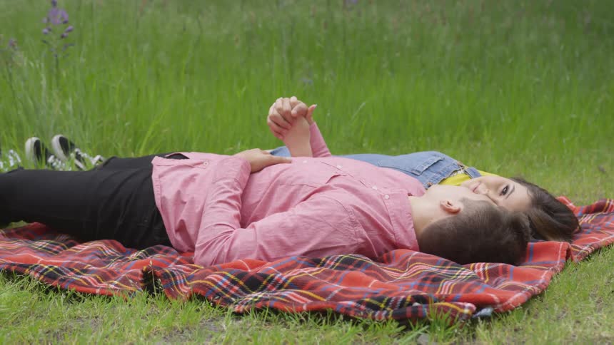 A man and woman are laying down in the grass