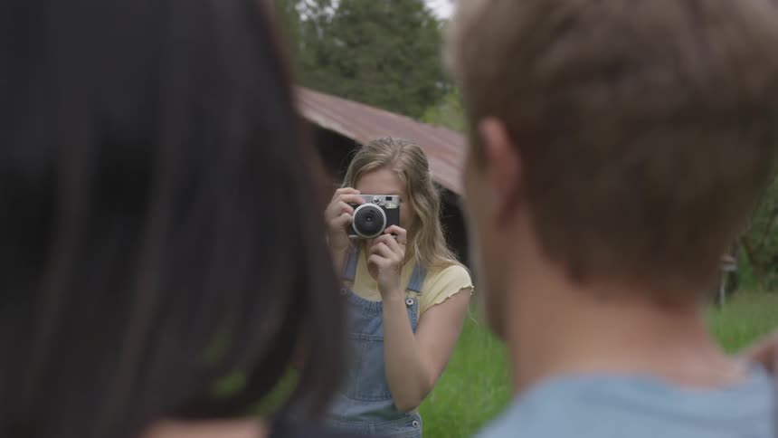 A man and woman being photographed by a woman outdoors during the day
