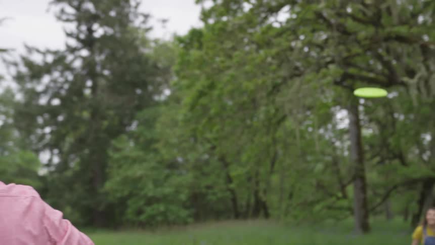 A man is throwing a frisbee to his daughter