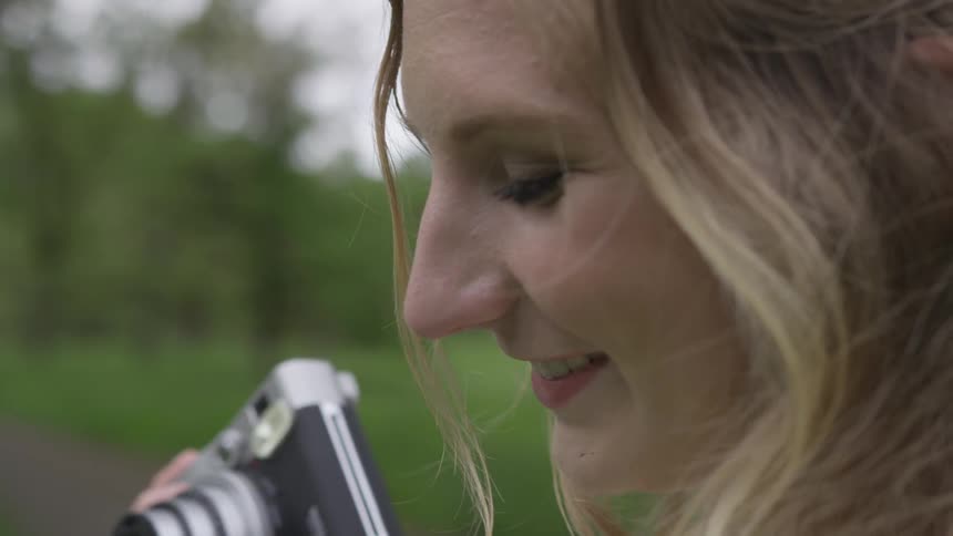 Young woman holding a camera and and photograph while smiling