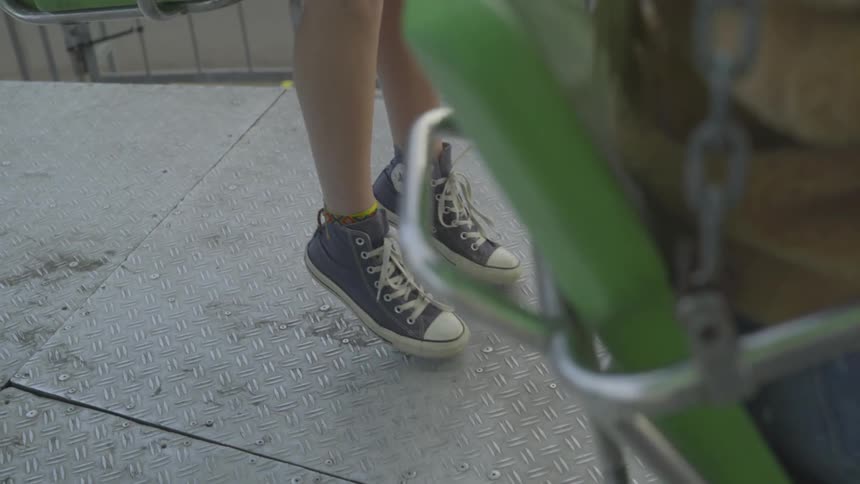 Two people sit in swings with their feet hanging down