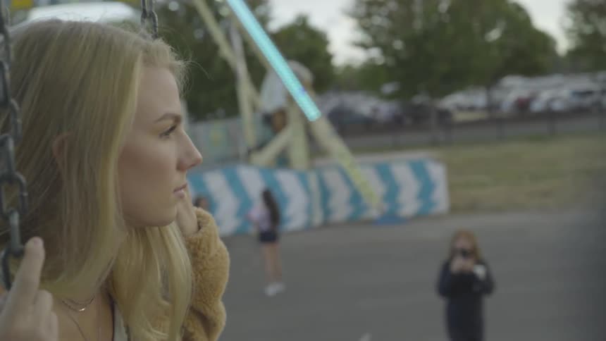 Girl sitting on a swing at a carnival