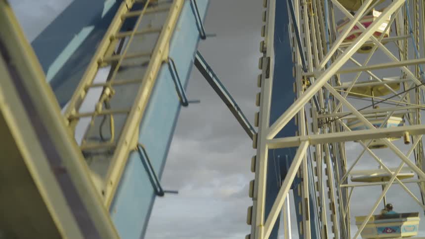 Ferris wheel spins with a man in it on a cloudy day