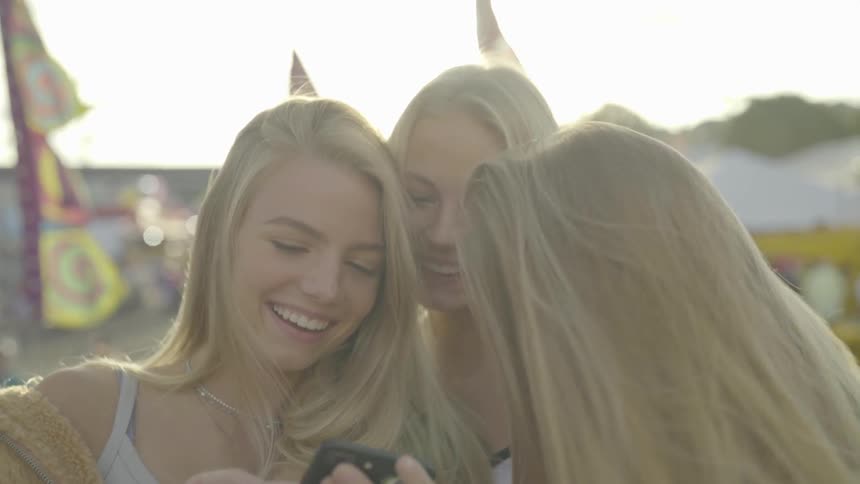 Three girls laughing over their phone