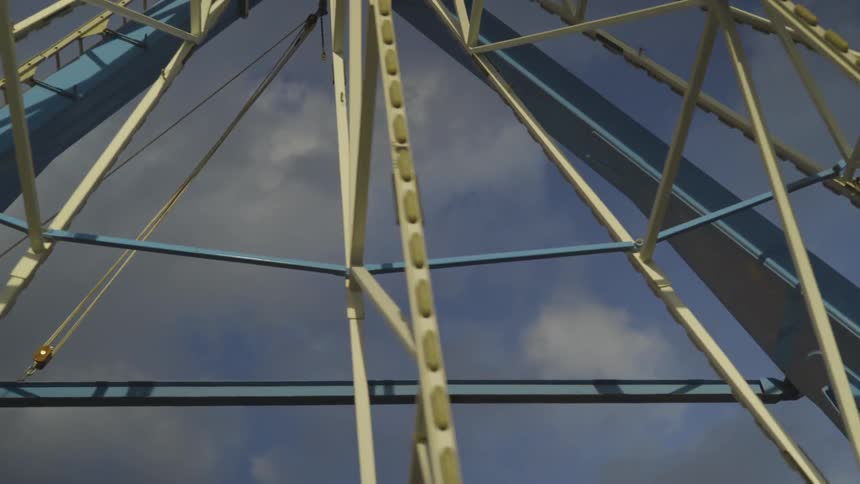 Ferris wheel turning against a blue sky with fluffy clouds
